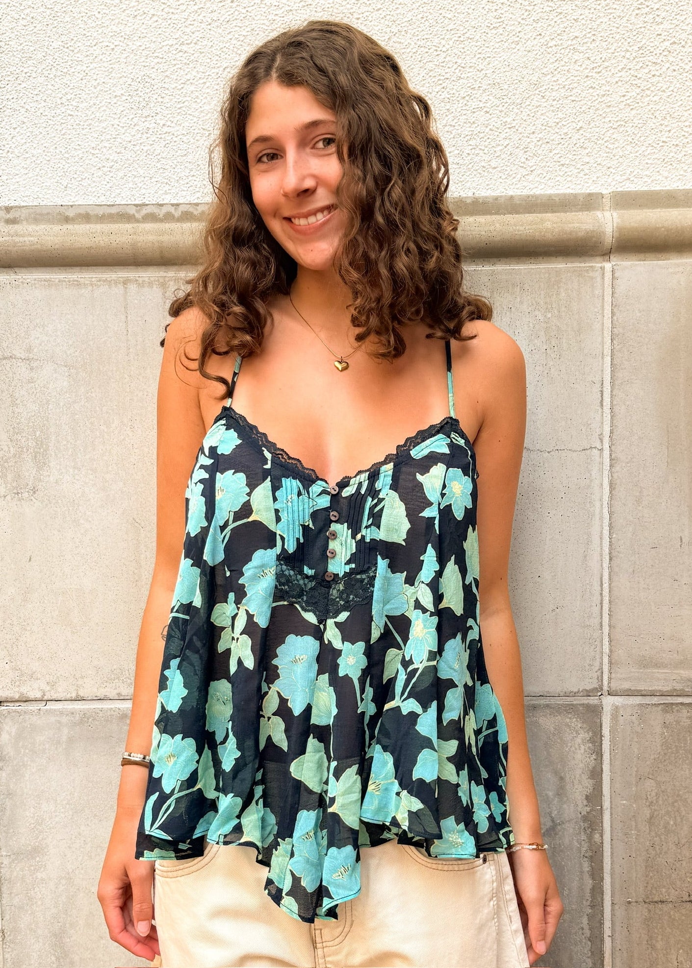 Woman wearing a floral top standing against a stone wall
